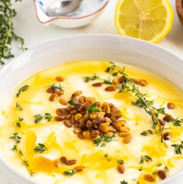 whipped Ricotta in the bowl garnished with fresh thyme, lemon zest, roasted pine nuts and honey