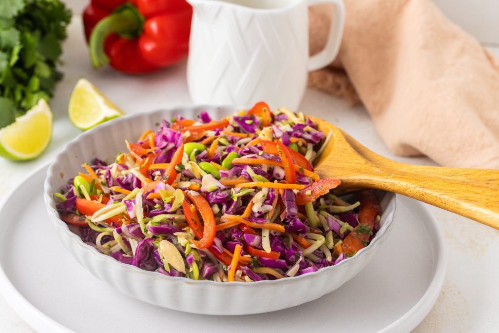 Colorful Asian cabbage salad with shredded green and purple cabbage, carrots, and sesame seeds, lightly dressed and served in a bowl.