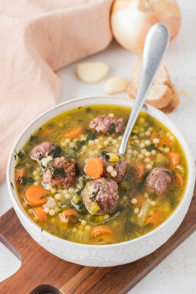 Bowl of homemade Italian wedding soup with meatballs, spinach, and pasta