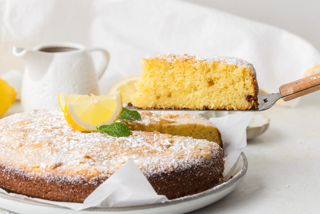 Lemon olive oil cake - one piece is being served on spatula