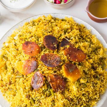 Fluffy long-grain rice mixed with tomato-braised green beans and meat, with golden saffron rice on top.