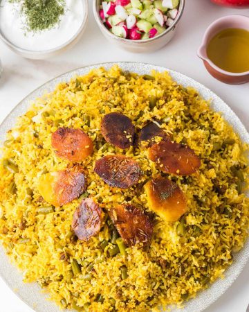 Fluffy long-grain rice mixed with tomato-braised green beans and meat, with golden saffron rice on top.