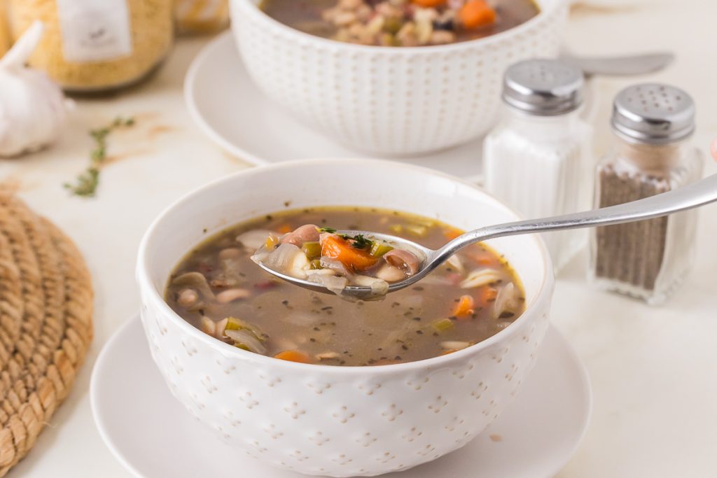 bowl of soup with spoon full of beans and vegetables