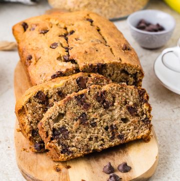 Moist banana bread loaf made with freshly milled flour, sliced and served on a wooden cutting board.