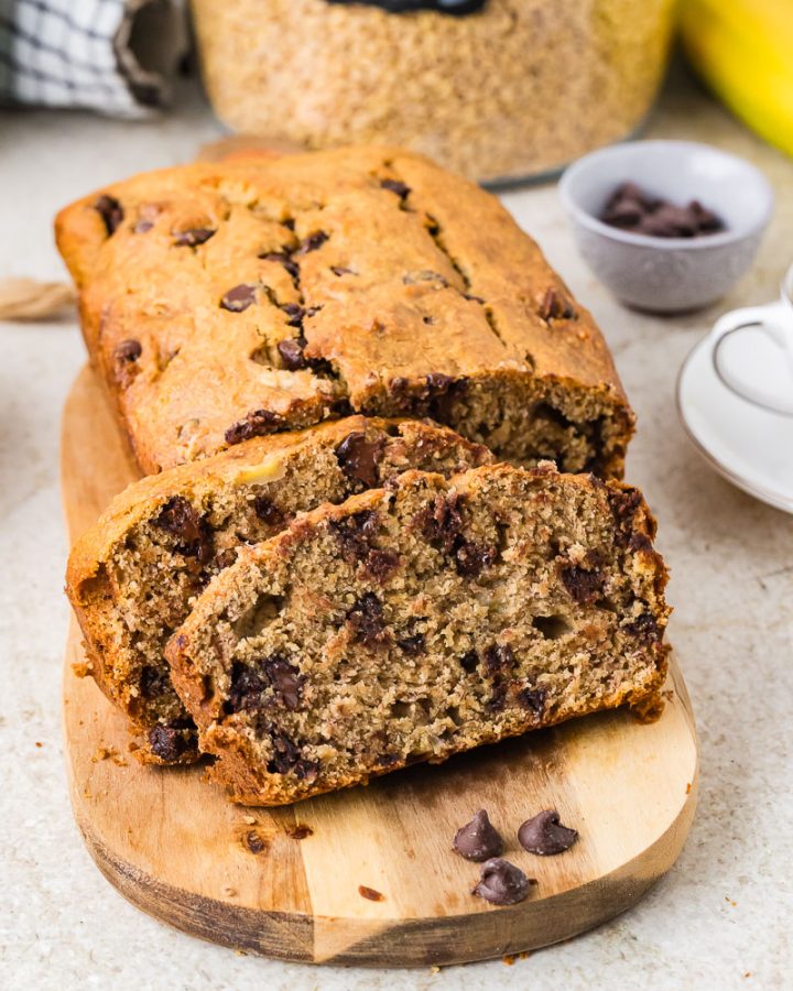 Moist banana bread loaf made with freshly milled flour, sliced and served on a wooden cutting board.