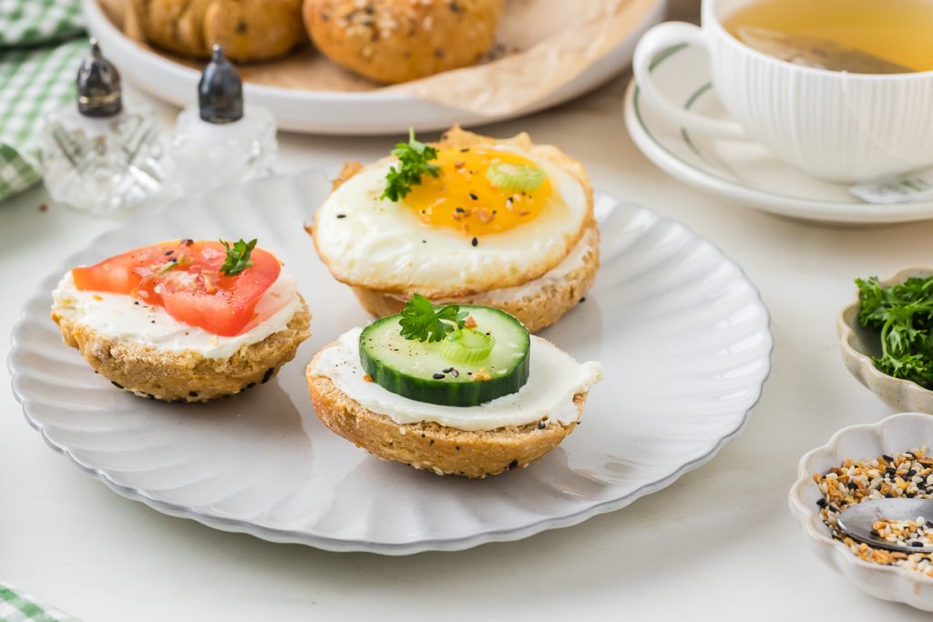 bagel with cream cheese and tomato, cucumber and fried egg